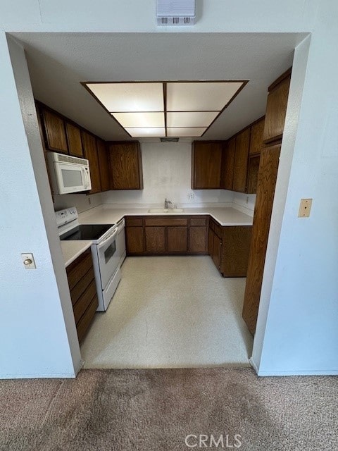 kitchen with light carpet, sink, and white appliances