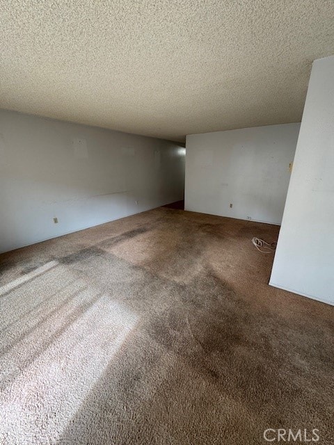 empty room featuring a textured ceiling and carpet flooring