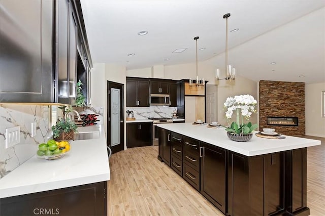 kitchen with decorative backsplash, hanging light fixtures, a center island, light hardwood / wood-style floors, and stainless steel appliances