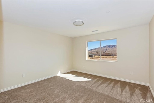 unfurnished room with a mountain view and carpet floors