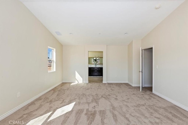 interior space featuring ensuite bathroom and light colored carpet