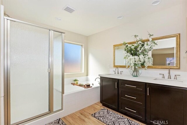 bathroom with hardwood / wood-style flooring, vanity, and plus walk in shower