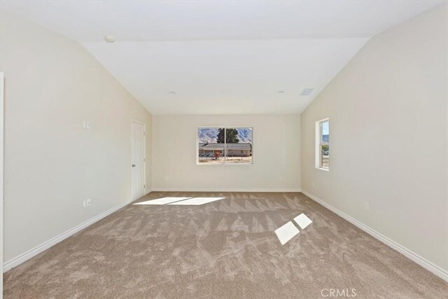 carpeted spare room with lofted ceiling