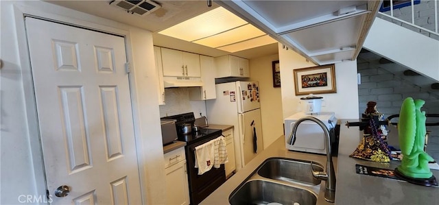 kitchen featuring black electric range oven, sink, tasteful backsplash, white fridge, and white cabinets