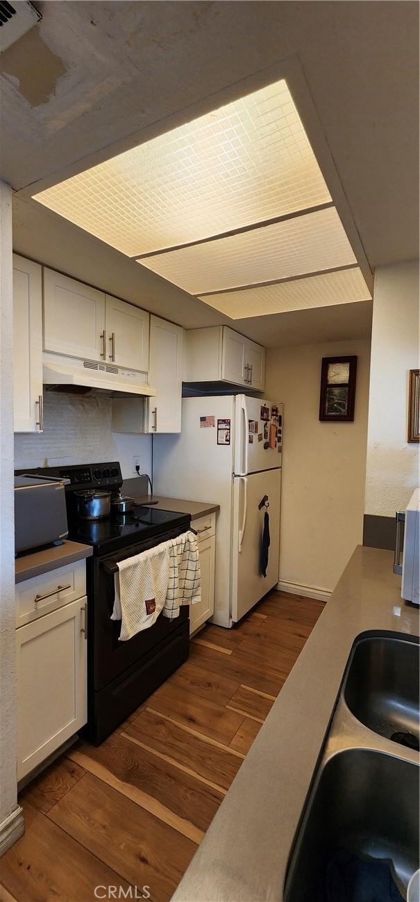 kitchen with sink, white cabinets, white refrigerator, dark wood-type flooring, and black electric range