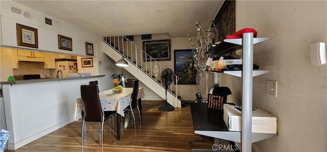 dining room with dark hardwood / wood-style floors, a textured ceiling, and brick wall