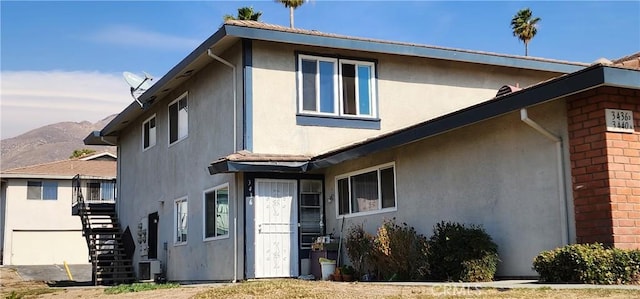 exterior space with a mountain view, stairway, and stucco siding