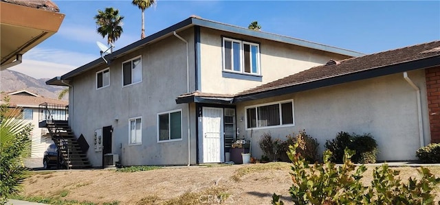 rear view of house with stairway and stucco siding