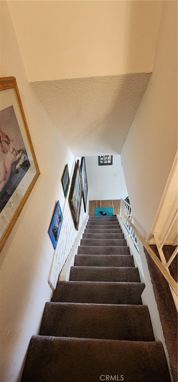 stairs featuring a textured ceiling