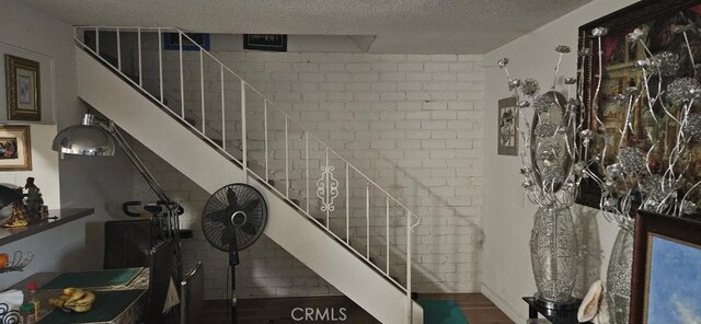 staircase with hardwood / wood-style flooring and a textured ceiling