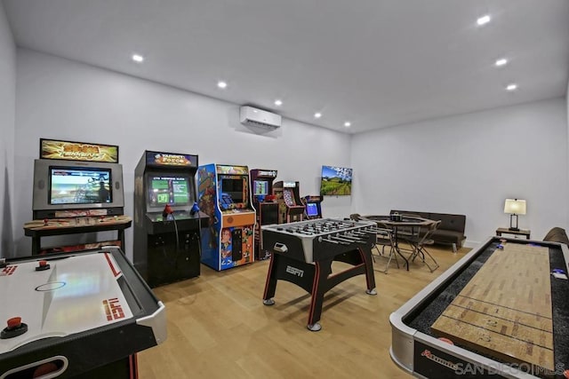 recreation room with light wood-type flooring and a wall unit AC