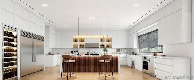 kitchen featuring a breakfast bar, decorative light fixtures, appliances with stainless steel finishes, a kitchen island, and white cabinets