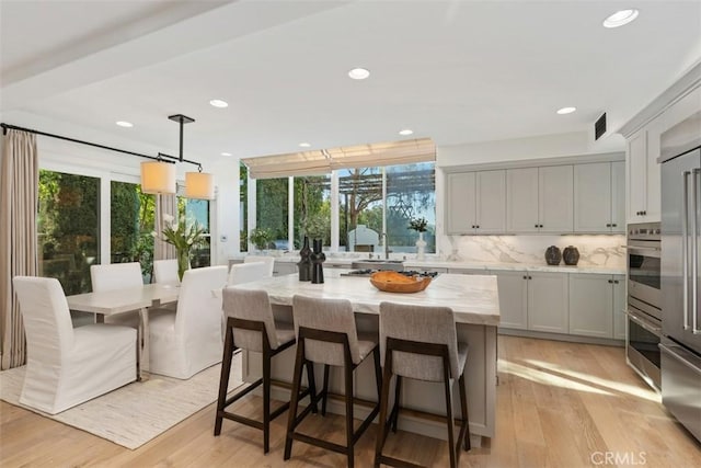 kitchen featuring decorative backsplash, light stone countertops, light wood finished floors, and a kitchen island