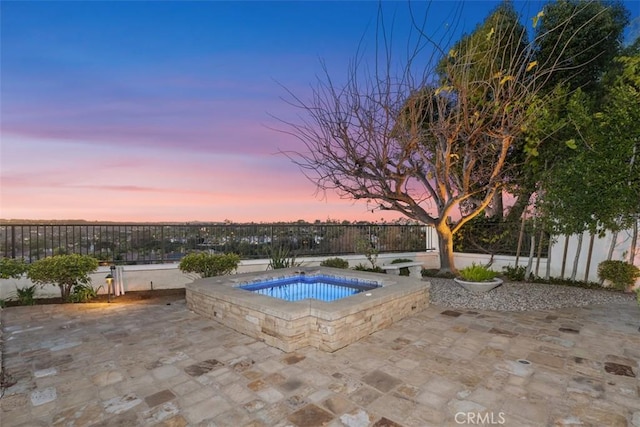 pool at dusk featuring fence and a patio