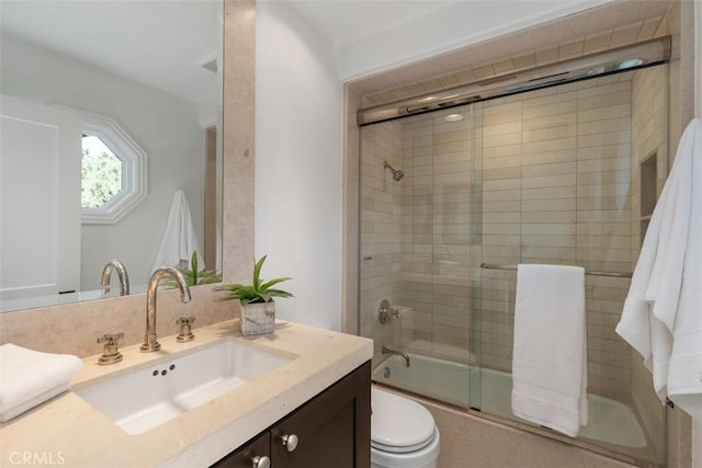 bathroom featuring vanity, toilet, and bath / shower combo with glass door