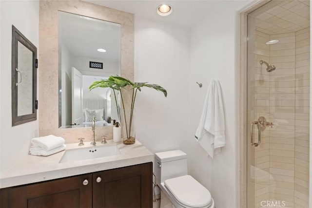 bathroom with vanity, a shower stall, and toilet