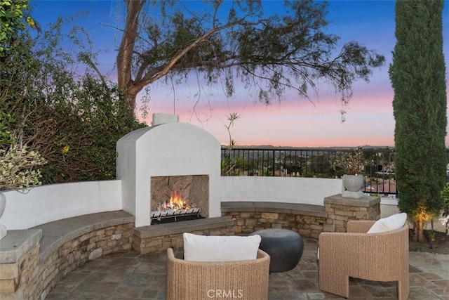 view of patio / terrace featuring a lit fireplace and fence