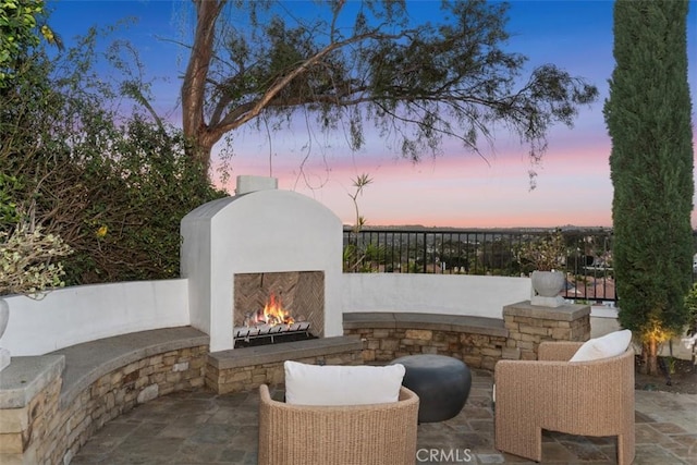 view of patio / terrace with a warm lit fireplace and fence