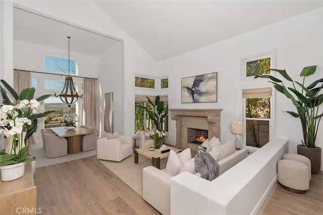 sitting room featuring a tiled fireplace, high vaulted ceiling, and wood finished floors