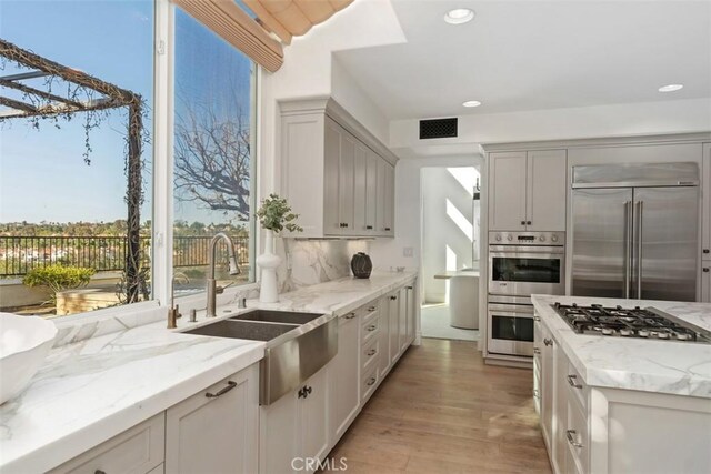 35 Brindisi, Laguna Niguel, CA 92677 - kitchen with stainless steel appliances, light wood-type flooring, light stone countertops, recessed lighting, and decorative backsplash