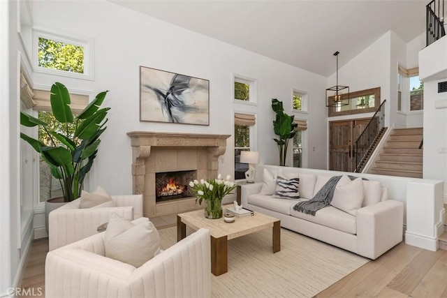 living area with stairs, plenty of natural light, wood finished floors, and a tile fireplace