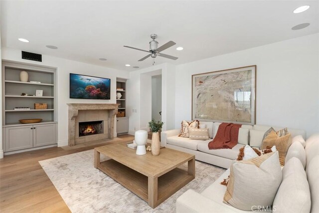 living room featuring a tiled fireplace, recessed lighting, and light wood finished floors