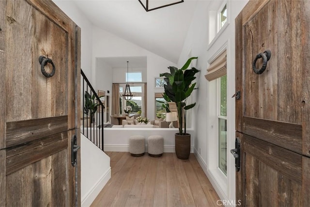 entryway with stairs, hardwood / wood-style flooring, a wealth of natural light, and high vaulted ceiling