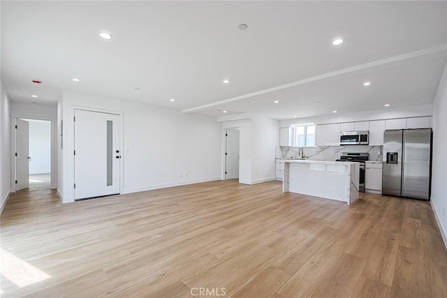 unfurnished living room featuring sink and light wood-type flooring