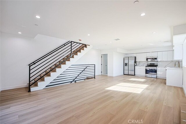 unfurnished living room with sink and light wood-type flooring