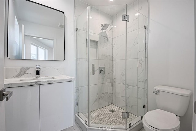 bathroom with vanity, toilet, and a shower with door