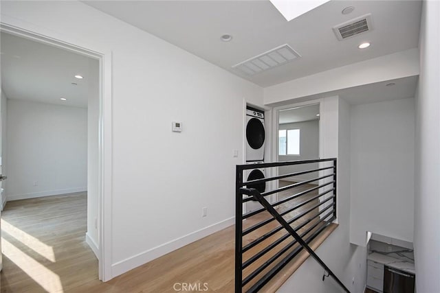 hall featuring stacked washer / dryer and light wood-type flooring