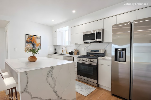 kitchen with a kitchen island, appliances with stainless steel finishes, tasteful backsplash, white cabinetry, and a kitchen breakfast bar