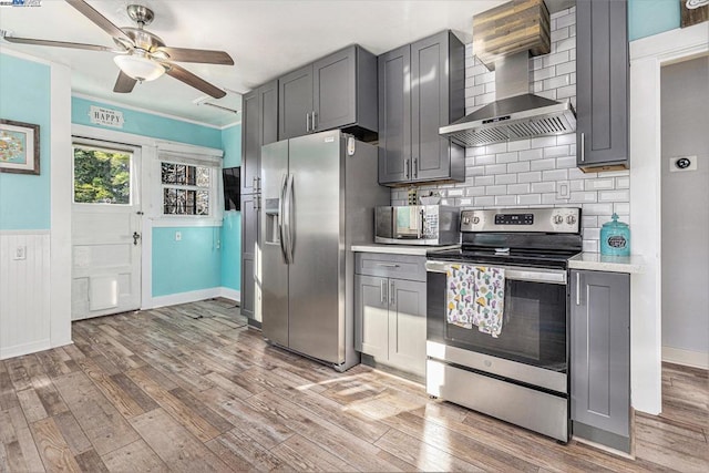 kitchen with wall chimney exhaust hood, stainless steel appliances, gray cabinets, and light hardwood / wood-style floors