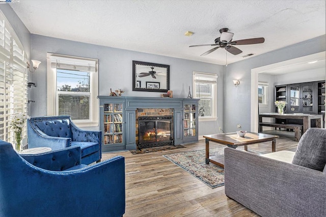 living room featuring hardwood / wood-style flooring, ceiling fan, and a textured ceiling