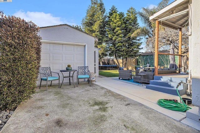 view of patio / terrace featuring a garage, an outdoor structure, and a trampoline