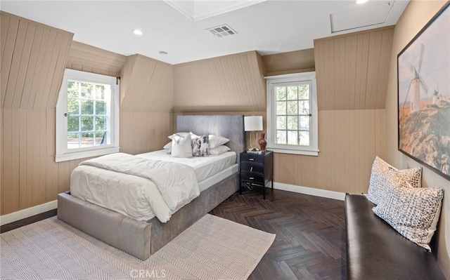 bedroom with multiple windows, dark parquet flooring, and wood walls