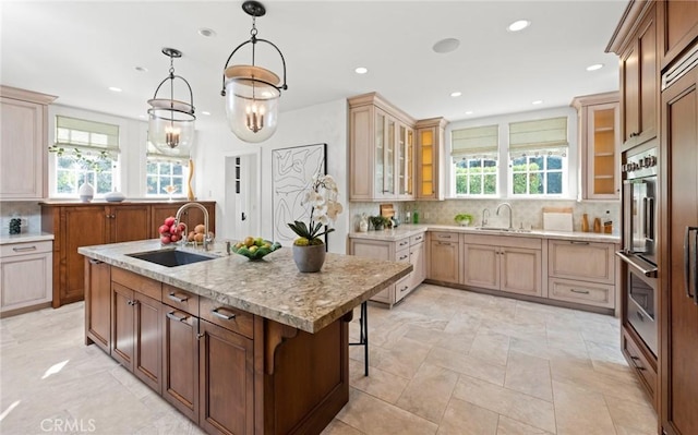 kitchen featuring pendant lighting, sink, a breakfast bar area, a kitchen island with sink, and tasteful backsplash