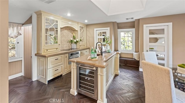 kitchen with a center island with sink, cream cabinets, stainless steel oven, and wine cooler