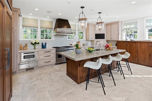 kitchen featuring a kitchen island with sink, custom range hood, a healthy amount of sunlight, and appliances with stainless steel finishes