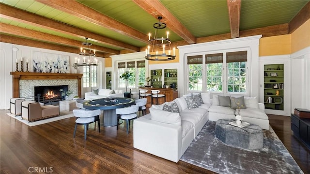 living room with wood ceiling, a chandelier, dark hardwood / wood-style flooring, a tile fireplace, and beam ceiling