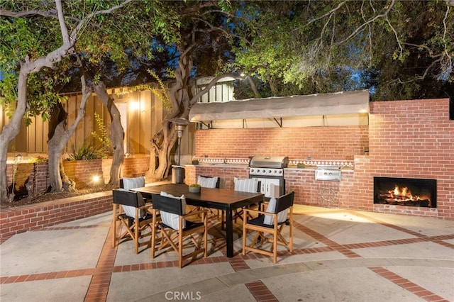 view of patio with an outdoor brick fireplace, grilling area, and exterior kitchen