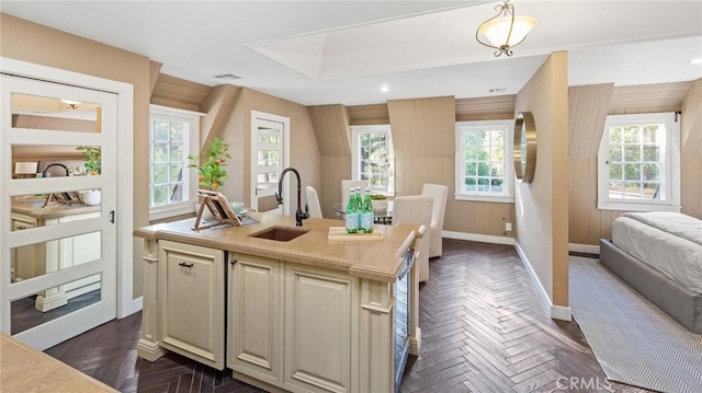 kitchen with sink, plenty of natural light, an island with sink, and wooden walls