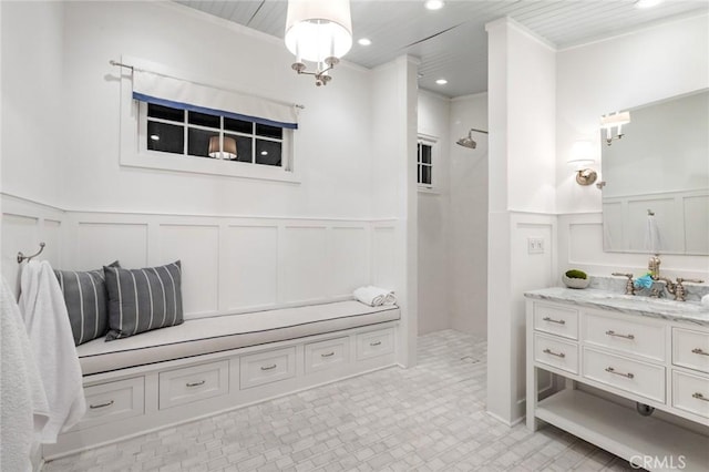 bathroom with vanity, ornamental molding, and a tile shower