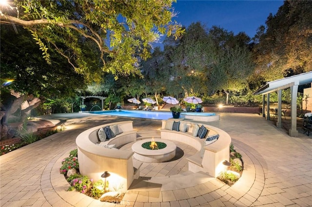 patio at night featuring pool water feature and an outdoor fire pit