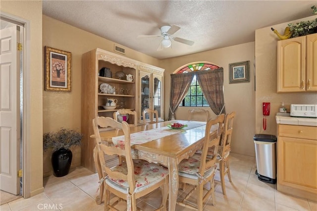 tiled dining space with ceiling fan and a textured ceiling