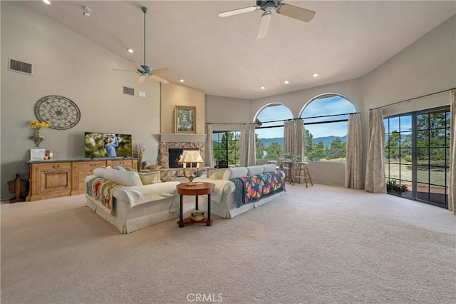 carpeted living room featuring ceiling fan, a high end fireplace, and high vaulted ceiling