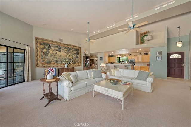 living room with light carpet, a towering ceiling, a wealth of natural light, and ceiling fan