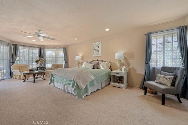 bedroom featuring ceiling fan, light colored carpet, and a textured ceiling