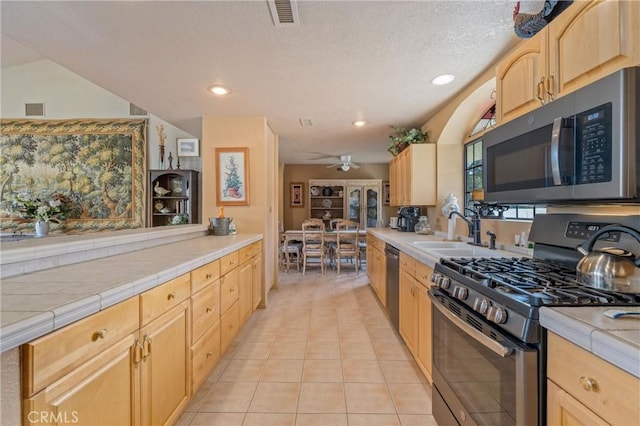 kitchen with appliances with stainless steel finishes, tile countertops, sink, light tile patterned floors, and light brown cabinets