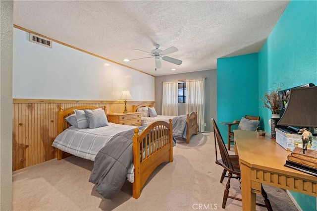 bedroom with ceiling fan, wooden walls, light carpet, and a textured ceiling